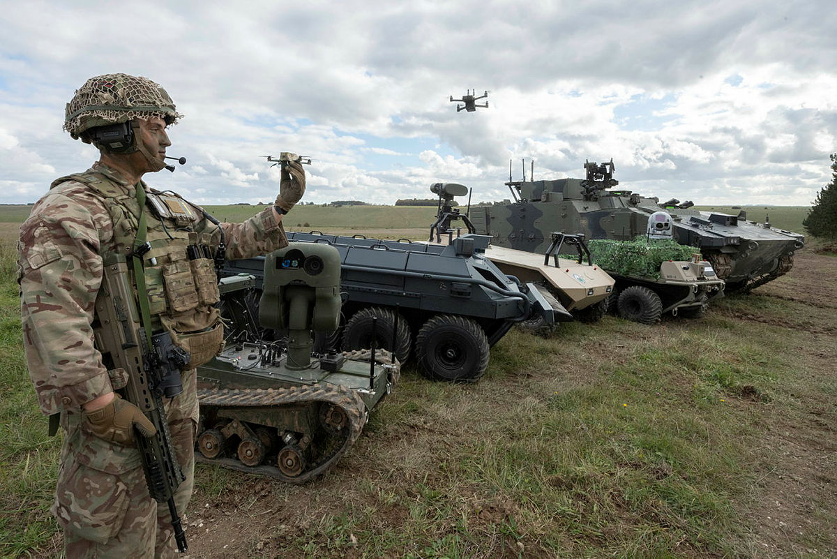 soldier is holding a drone and stand with other unmanned platforms